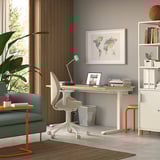 Home office moderno con divano verde, divisorio in legno, scrivania in legno, sedia ergonomica bianca, decorazioni con mappa del mondo e ripiani portaoggetti.