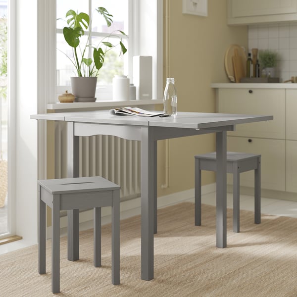 Elegante tavolo a ribalta HAUGA grigio con sgabelli. Perfetto per piccoli spazi, si estende fino a 4 posti a sedere. Design moderno con impiallacciatura in legno e pino massiccio.