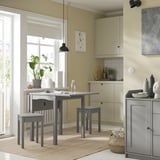 Accogliente angolo cucina con tavolo e sgabelli grigi HAUGA, tappeto beige e pianta in vaso.