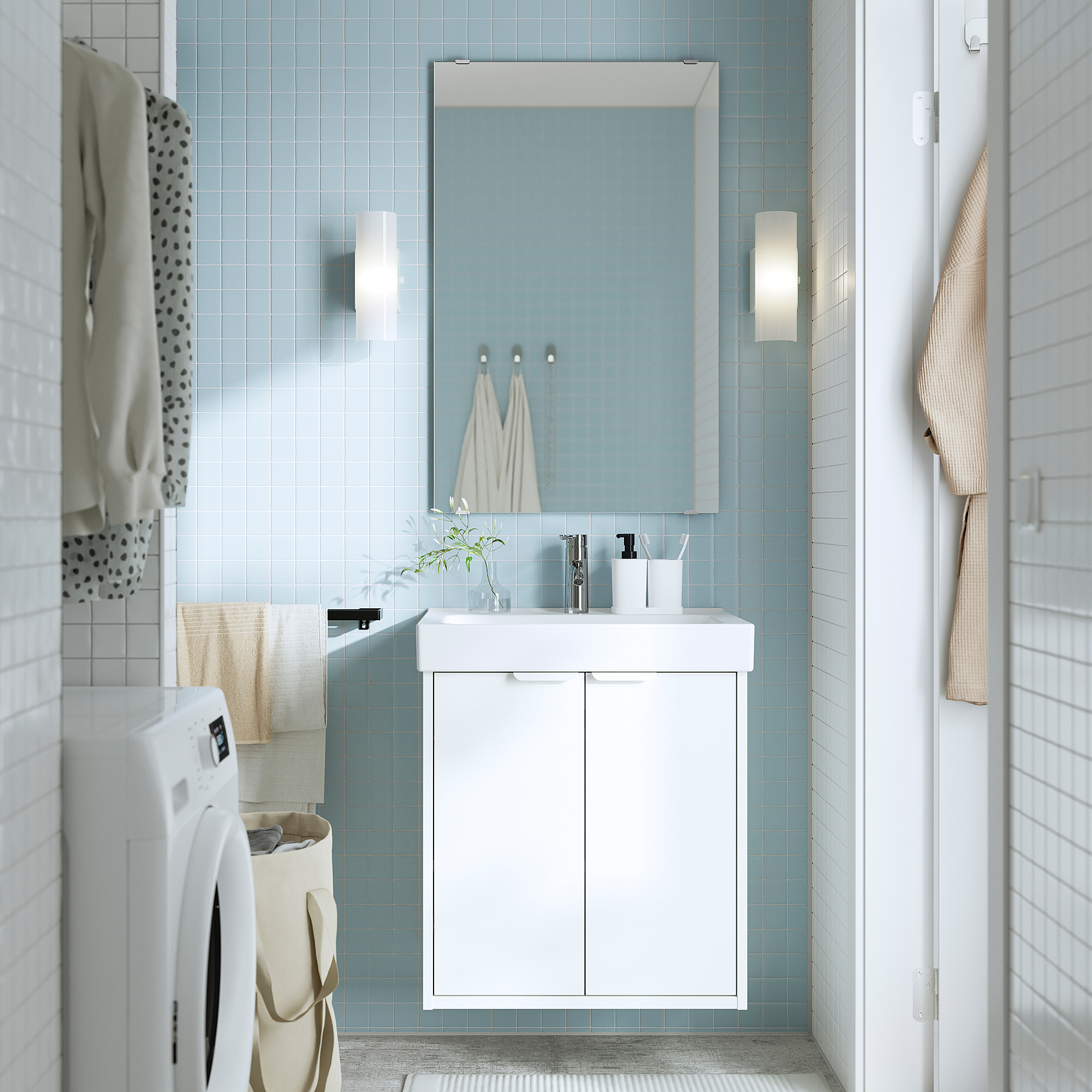 Bagno moderno con mobile HAVBÄCK bianco, lavandino e specchio, completato da piastrelle blu e asciugamani appesi.