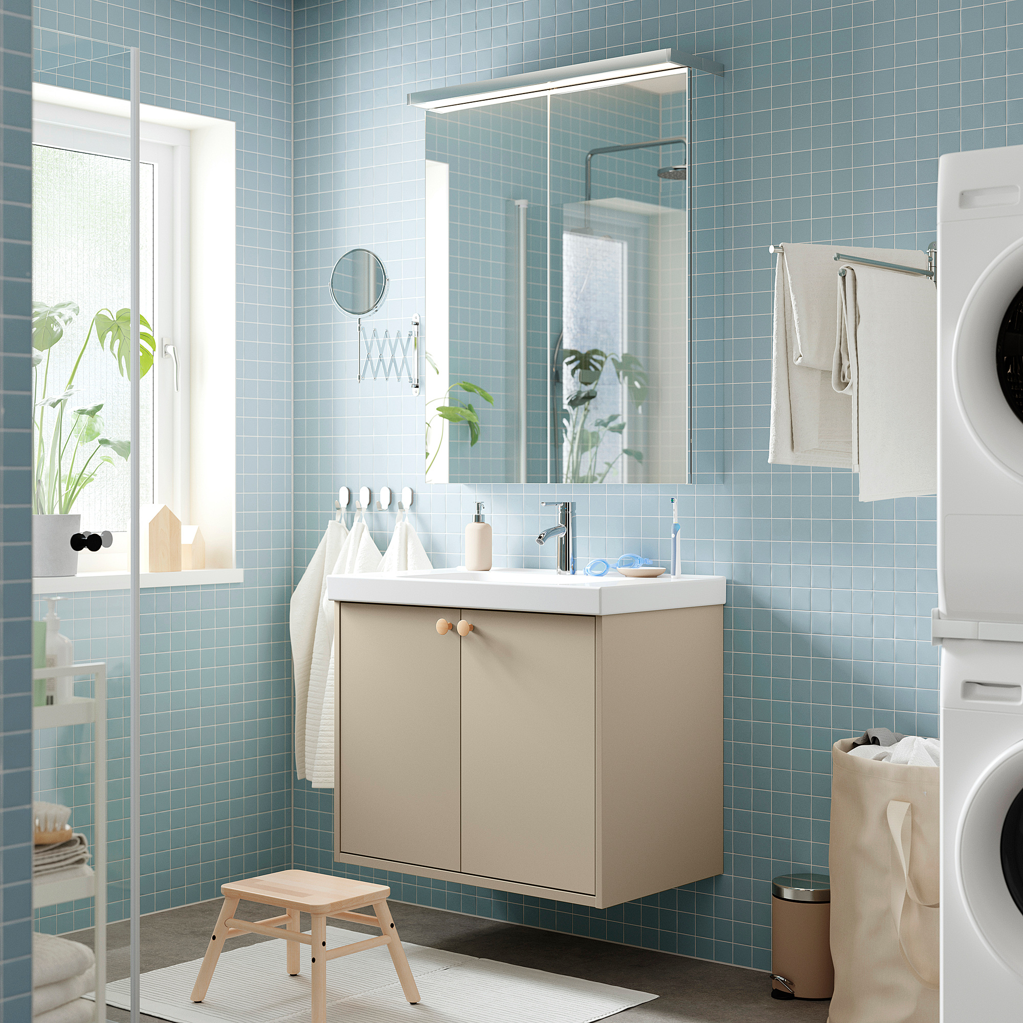 Vanità beige, lavandino bianco, bagno piastrellato blu con piante e asciugamani.