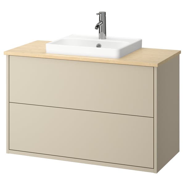 Un mobile da bagno HAVBÄCK beige con piano di lavoro in bambù e lavandino quadrato in ceramica bianca.