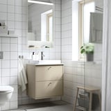 Mobile HAVBÄCK: beige, sospeso con lavabo e cassetti. Piastrelle bianche, specchio, asciugamani, sgabello.