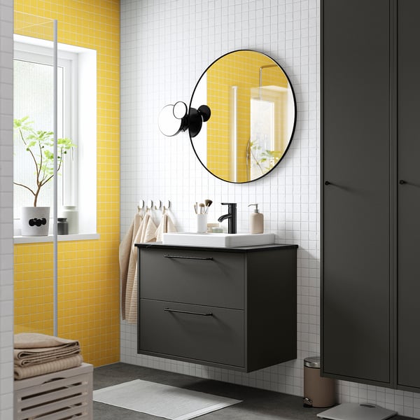 Bagno moderno: lavandino grigio, lavabo bianco, specchio rotondo, parete gialla.