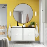 Bagno moderno con lavabo HAVBÄCK, parete piastrellata gialla, grande specchio e ripostiglio.