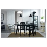 Moderna zona pranzo con tavolo e sedie nere, lampade a sospensione e accenti in uno spazio pulito e minimalista.