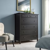 Camera da letto moderna con comò HEMNES, specchio, sedia grigia e letto.