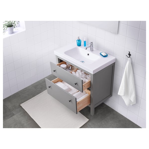 Moderno mobile da bagno con cassetti aperti che rivelano l'organizzazione, lavandino bianco e armadietto grigio.