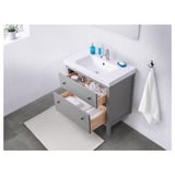 Moderno mobile da bagno con cassetti aperti che rivelano l'organizzazione, lavandino bianco e armadietto grigio.