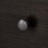 Superficie in legno scuro con maniglia rotonda in metallo per cassetti, che mostra un design elegante e una lavorazione artigianale di alta qualità.