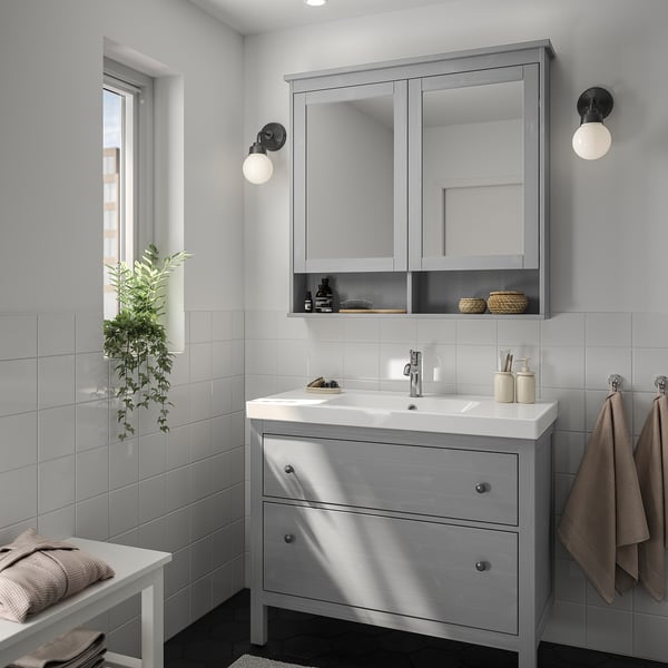 Moderna configurazione del bagno grigio. HEMNES vanità, armadietto a specchio, asciugamani e piante. La vanità si inserisce tra lo specchio e la finestra.