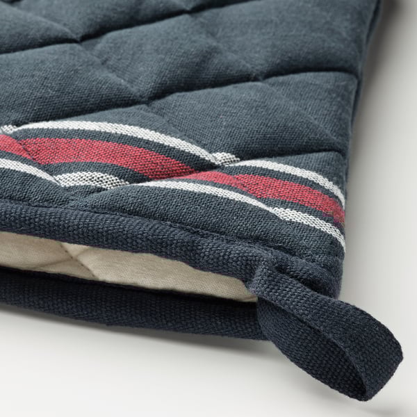 Un primo piano di un angolo cuscino a righe blu scuro e rosse, legato con tessuto blu scuro, che mette in mostra materiali di alta qualità e artigianalità.