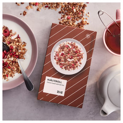 Scatola aperta di muesli con muesli e frutti di bosco, ciotola per yogurt, tazza rosa, marca IKEA.