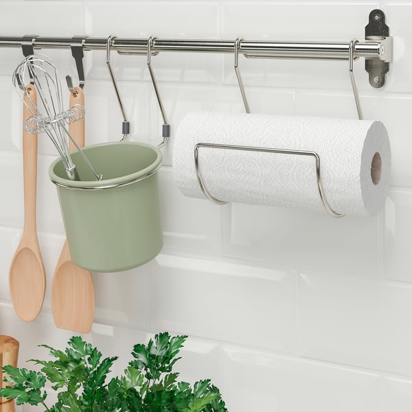 Il binario in metallo con ganci contiene la tazza verde e il tovagliolo di carta per la conservazione in cucina.