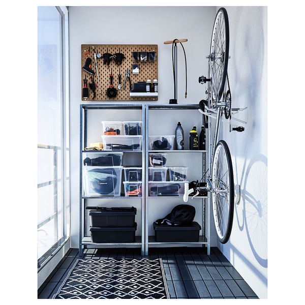 Area di stoccaggio organizzata con ripiani contenenti oggetti vari; La bicicletta si appoggia al muro.