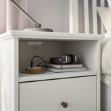 Comodino IDANÄS bianco con ripiani, cuffie, libri, lampada.