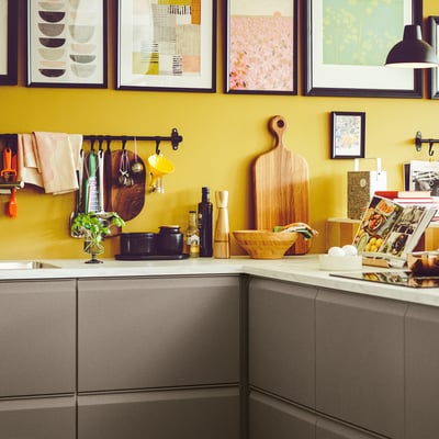 Cucina gialla con armadietti grigi, strumenti da cucina e oggetti da bancone.