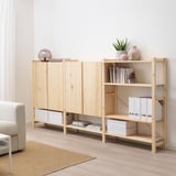 Mobile contenitore IVAR in legno chiaro, con ripiani e un mobile. Contiene vari oggetti, posizionati vicino a un divano beige in una stanza luminosa.