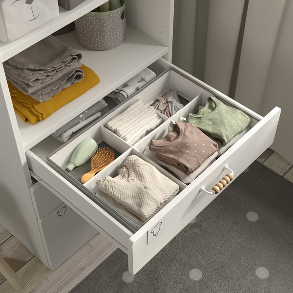 Cassetto organizzato con vestiti ben piegati in sezioni, una spazzola per capelli e accessori. Parte del sistema di organizzazione JÄTTEBJÖRN.