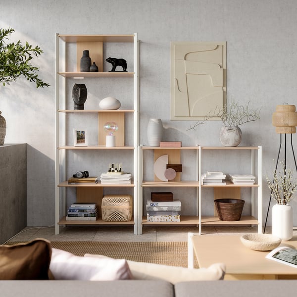 Soggiorno moderno, beige chiaro, con scaffali in legno chiaro pieni di libri e decorazioni. Arte astratta ed elementi naturali.