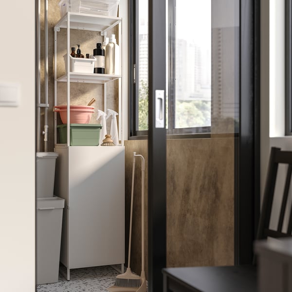 Lavanderia organizzata con ripiano bianco JOSTEIN contenente prodotti per la pulizia. Include secchi, bottiglie e spazzole disposti in modo ordinato.