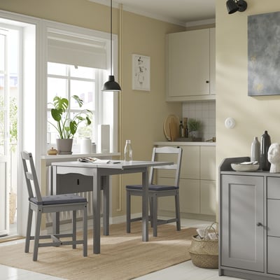 Accogliente sala da pranzo con tavolo grigio moderno e sedie abbinate, ampia finestra, tappeto beige e decorazioni.