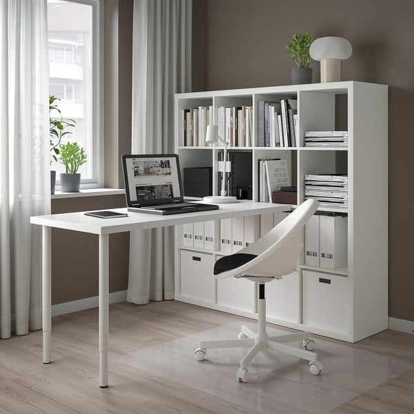 Home office moderno e minimalista con scaffale, scrivania e sedia KALLAX bianchi. Ampia finestra con tende trasparenti, pavimento in legno.