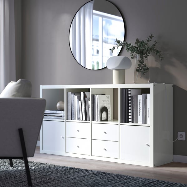 Soggiorno moderno con credenza KALLAX, libri, specchio, lampada e comoda sedia.