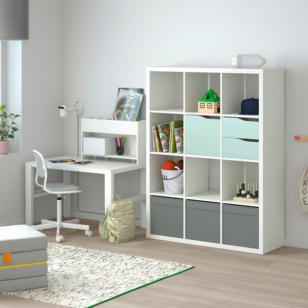 Moderna configurazione per lo studio dei bambini con scaffalatura KALLAX dotata di inserti per porte, libri, giocattoli e scrivania con sedia.