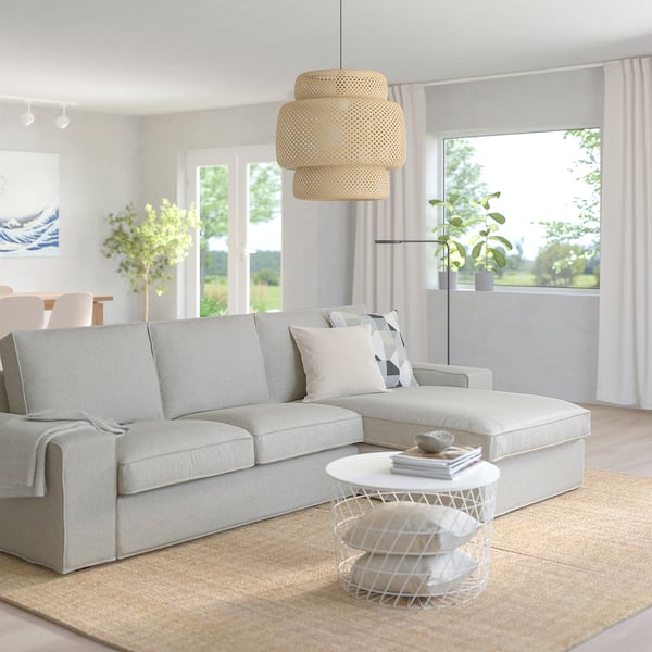 Divano KIVIK, tavolino, cuscini, luce naturale, luce sospesa, piante, tappeto beige.