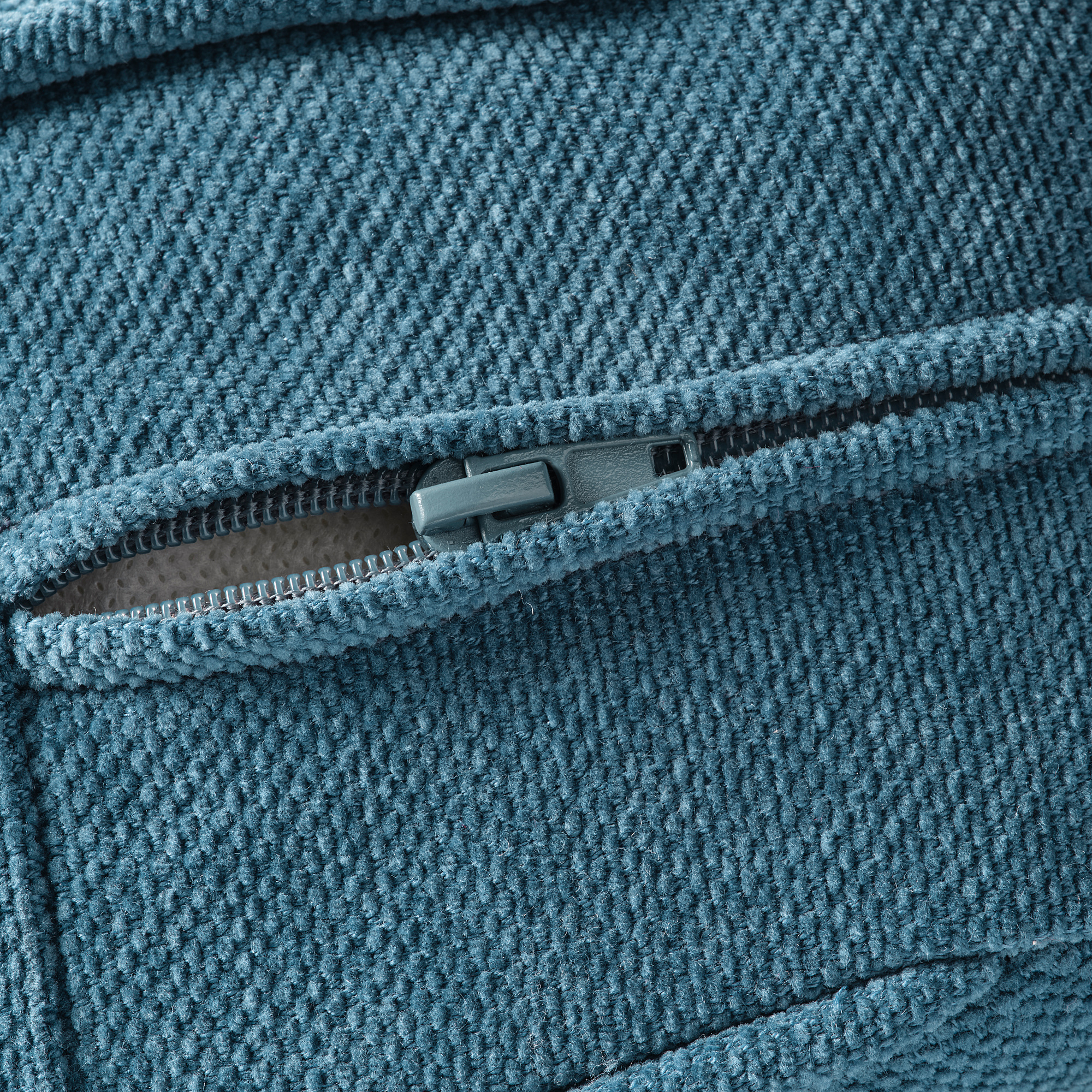 Primo piano di un'accogliente cerniera del divano KIVIK grigia, che mostra una trama del tessuto di qualità e un design durevole.