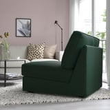 Divano letto verde moderno, pareti rosa, divano grigio con cuscini, lampada, libreria e vista finestra.