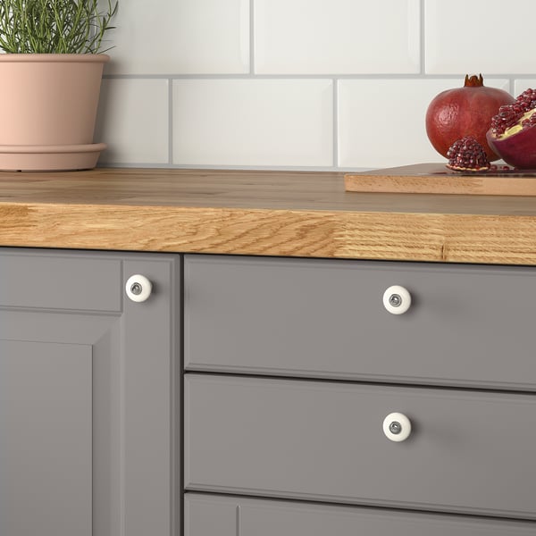 Cassetto da cucina grigio con piano in legno, pomelli KLINGSTORP, pianta in vaso e melograni.