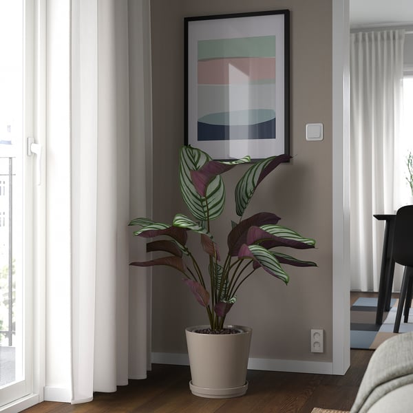 Soggiorno moderno con pianta in vaso grigia sotto l'arte colorata.