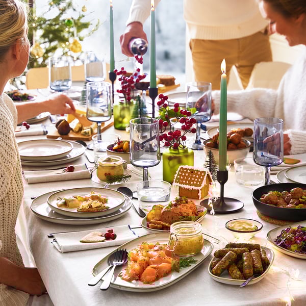 Tavola delle feste con barattoli KORKEN, sottaceti, candele e decorazioni festive.