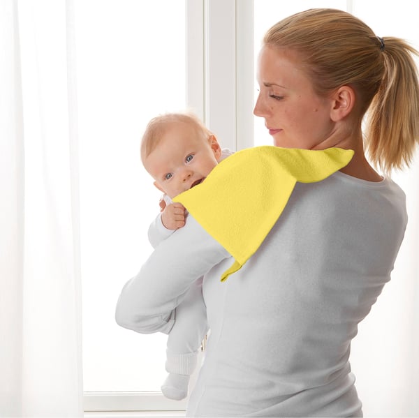 Una madre tiene un bambino con un panno giallo brillante sulla spalla del bambino, probabilmente per evitare fuoriuscite.