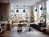 Ampio laboratorio con scrivania KULLABERG, piante e lampade nere, che offre un mix di legno naturale e stile moderno.