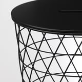 Moderno tavolino nero con elegante piano rotondo e intricata base in filo metallico, che offre uno spazio elegante per riporre gli oggetti.