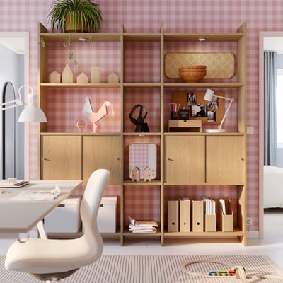 Home office con mensole LÅDMAKARE, libri, decorazioni, sedia, lampada, pareti rosa.