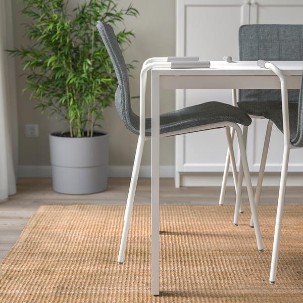 Ufficio minimalista con sedie moderne e impilabili e una pianta alta, che favorisce uno spazio di lavoro pulito ed efficiente.