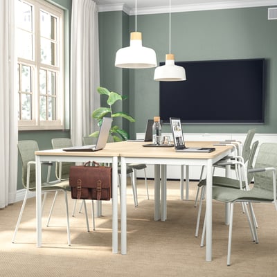 Ufficio moderno con pareti verdi, tv, tavolo in legno, sedie, laptop, pianta, borsa, due lampade a sospensione e una finestra con tende.