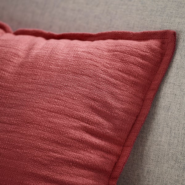 Cuscino rosso primo piano, bordo strutturato su grigio.