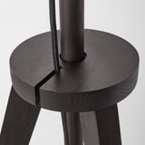 Primo piano della base moderna della lampada da terra in legno di alta qualità. Sedile rotondo, tre gambe robuste e tubo di supporto verticale centrale mostrato.