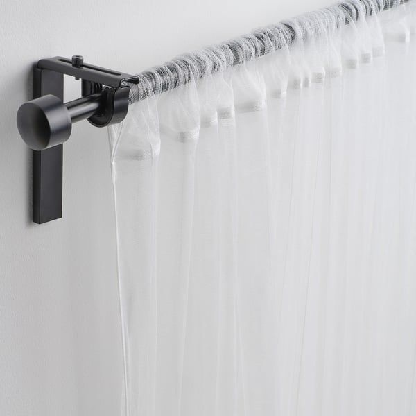 L'asta per tende nera contiene tende bianche trasparenti, consentendo luce e aria e garantendo privacy.