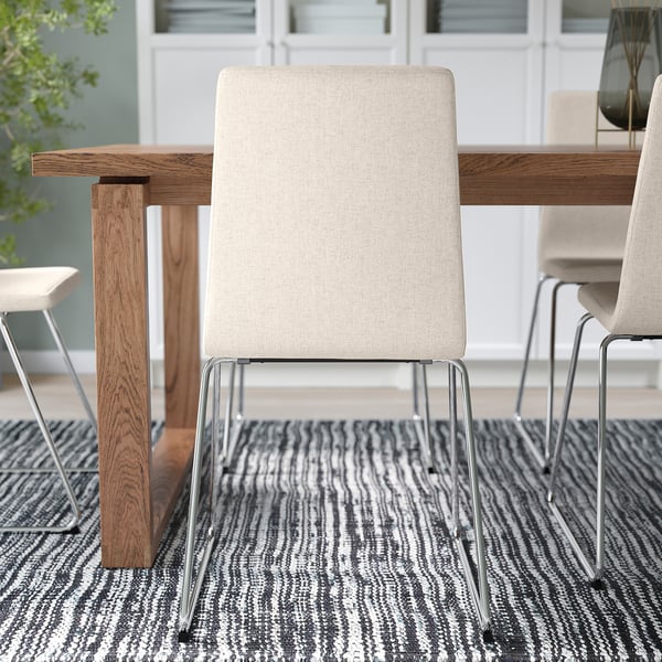 Sedia da pranzo moderna con rivestimento sfoderabile beige, base a slitta in metallo e sedile imbottito. Ideale per una facile pulizia e uno spazio limitato.