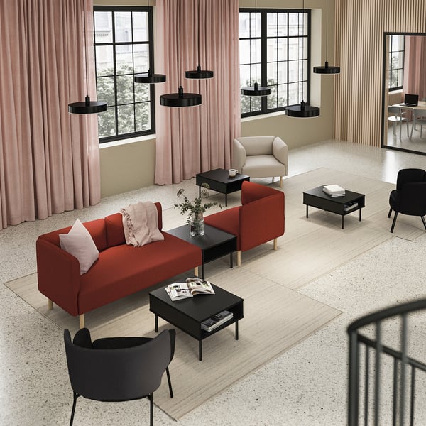 Soggiorno moderno con divano LILLEHEM rosso, tavolini neri, tende rosa e lampade a sospensione nere.