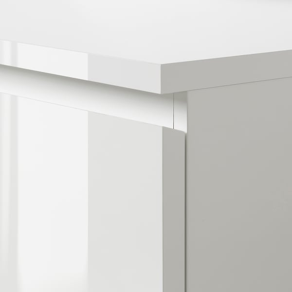 Un primo piano dell'elegante comò bianco MALM che mostra bordi lisci e linee pulite.