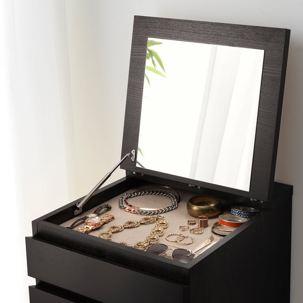 Portagioie in legno scuro con parte superiore a specchio, accessori esposti.