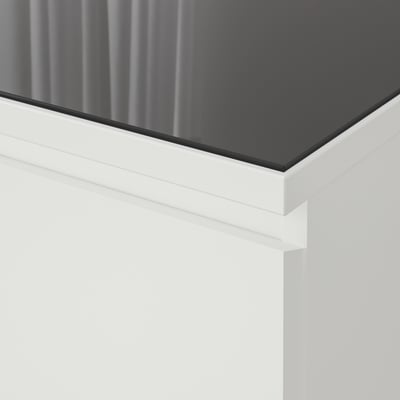 Primo piano di un tavolo elegante e moderno con piano in vetro nero lucido e bordi bianchi nitidi.