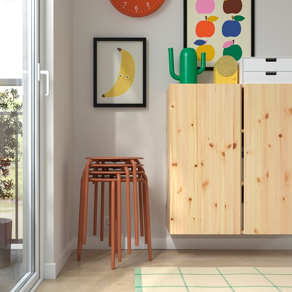 Sgabelli in legno impilati vicino all'armadio con decorazioni colorate.
